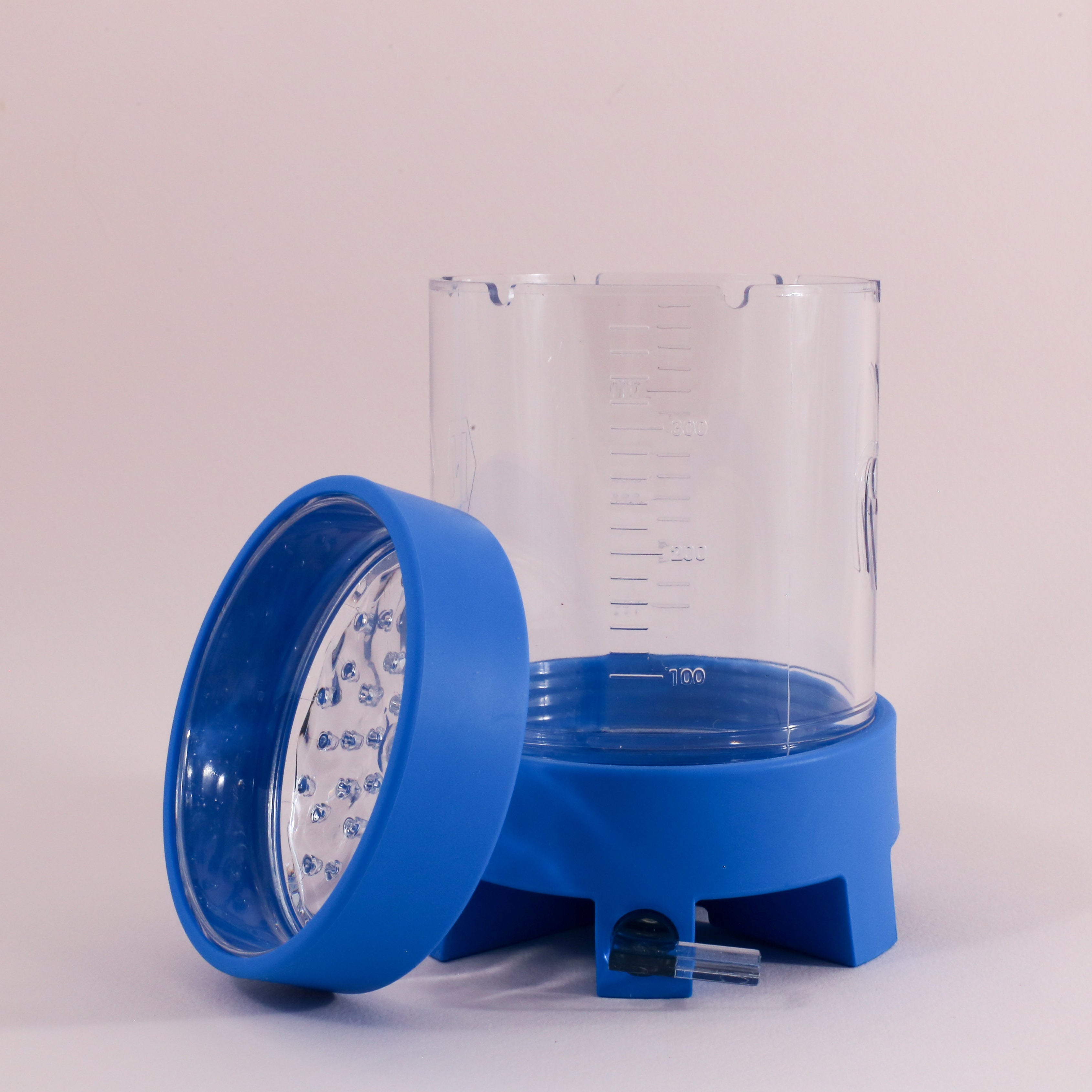 The NextLevel Pulsar Brewer by Tandem Coffee Roasters is a clear plastic manual coffee brewer with measurement markings, a blue lid resting beside it, and a matching blue base featuring an adjustable flow valve at the bottom.