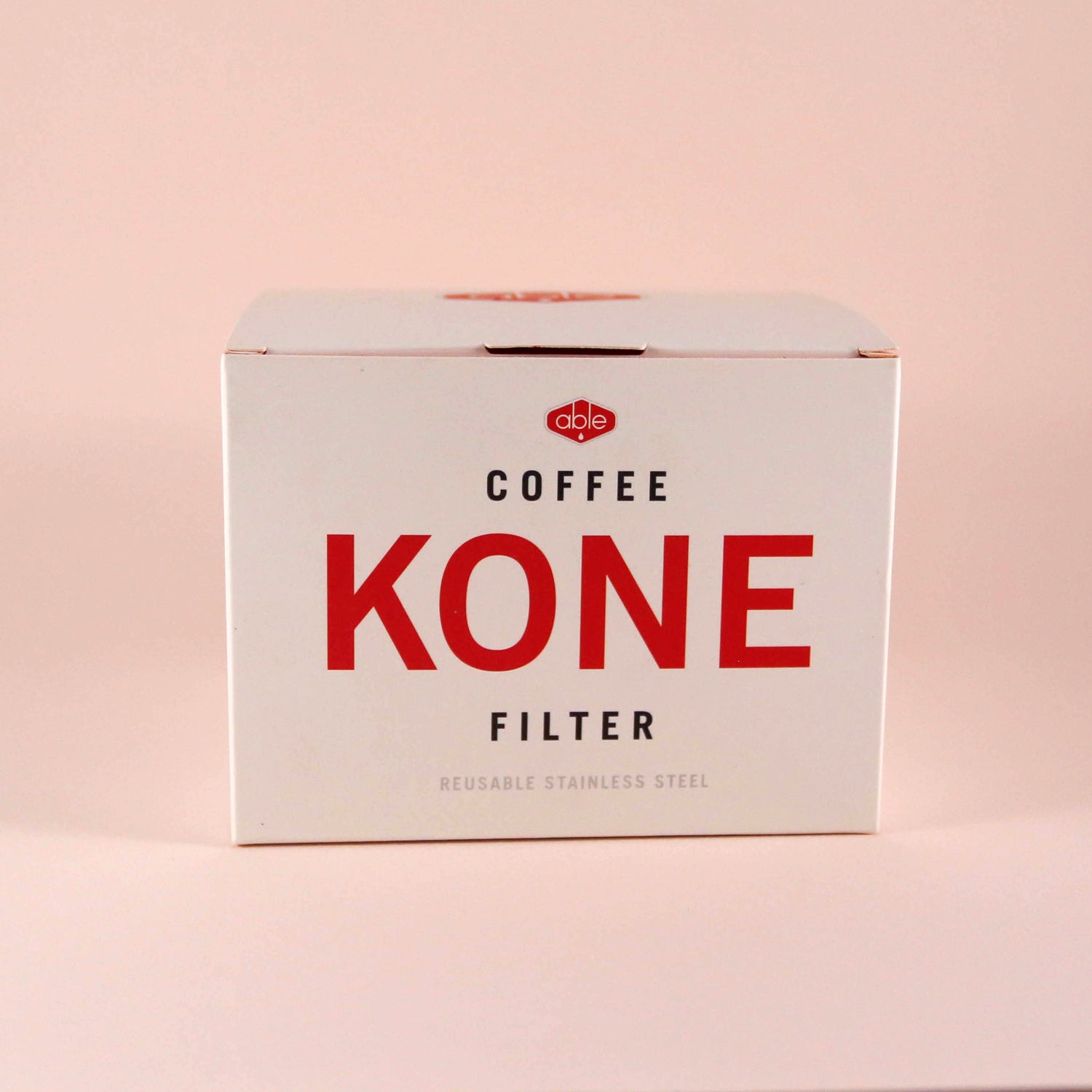 A box of reusable stainless steel Able Coffee Kone filter by Tandem Coffee Roasters, labeled "reusable stainless steel," against a pale pink background.