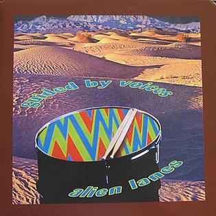 Colorful cover art for Guided By Voices - Alien Lanes from Tandem Coffee Roasters, showing a zigzag drum in a desert with mountains and blue album title text, referencing their Dayton heritage and the Wright Brothers.