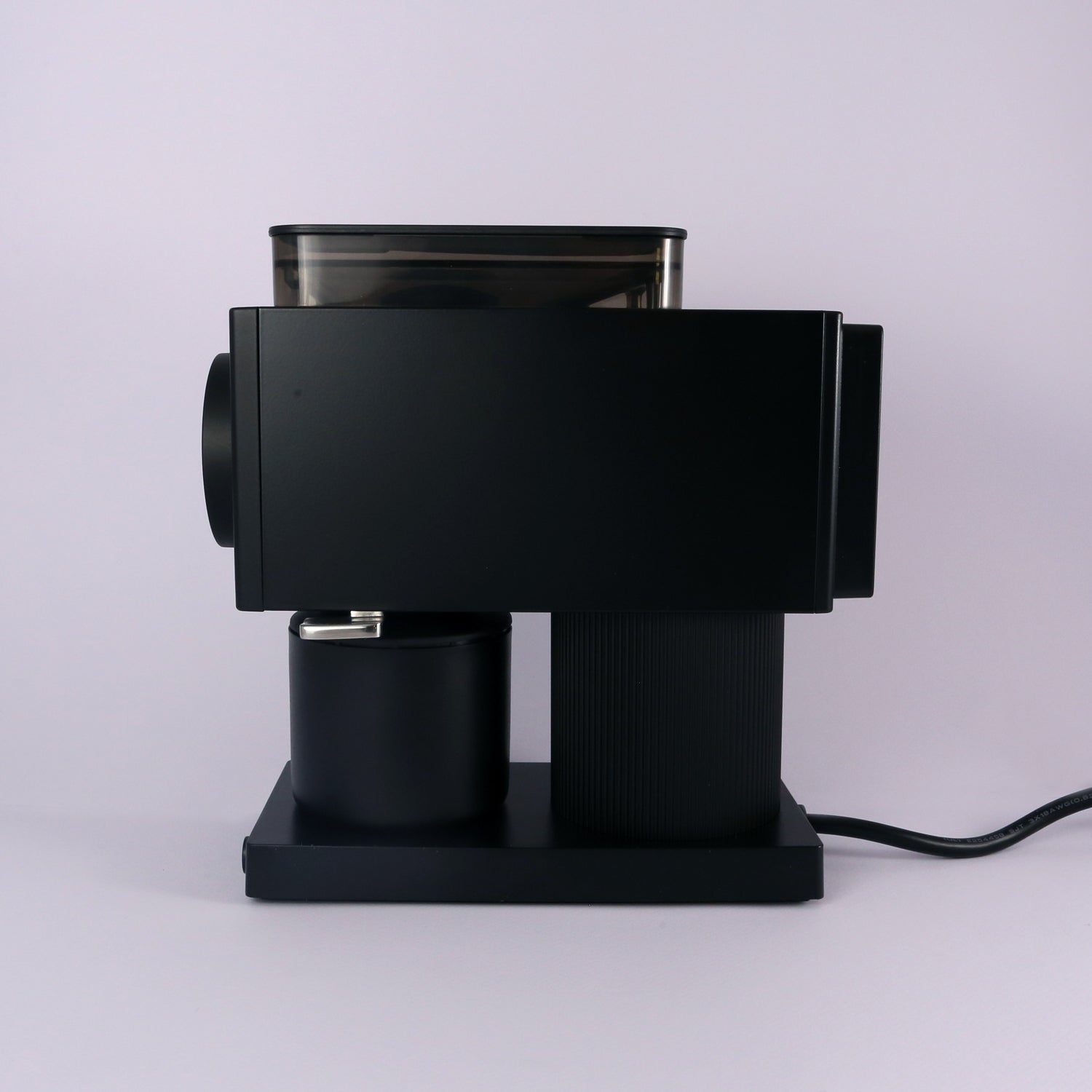 The Tandem Fellow Ode Brew Grinder Gen 2, a sleek black flat burr grinder, rests on a light gray surface with its power cord visible, set against a plain light background.