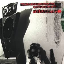 Black-and-white image: a person with headphones sits by large speakers. Red text reads “The Flaming Lips - Transmissions from the Satellite Heart.” Offered by Tandem Coffee Roasters; includes tracks like "She Don't Use Jelly.”.